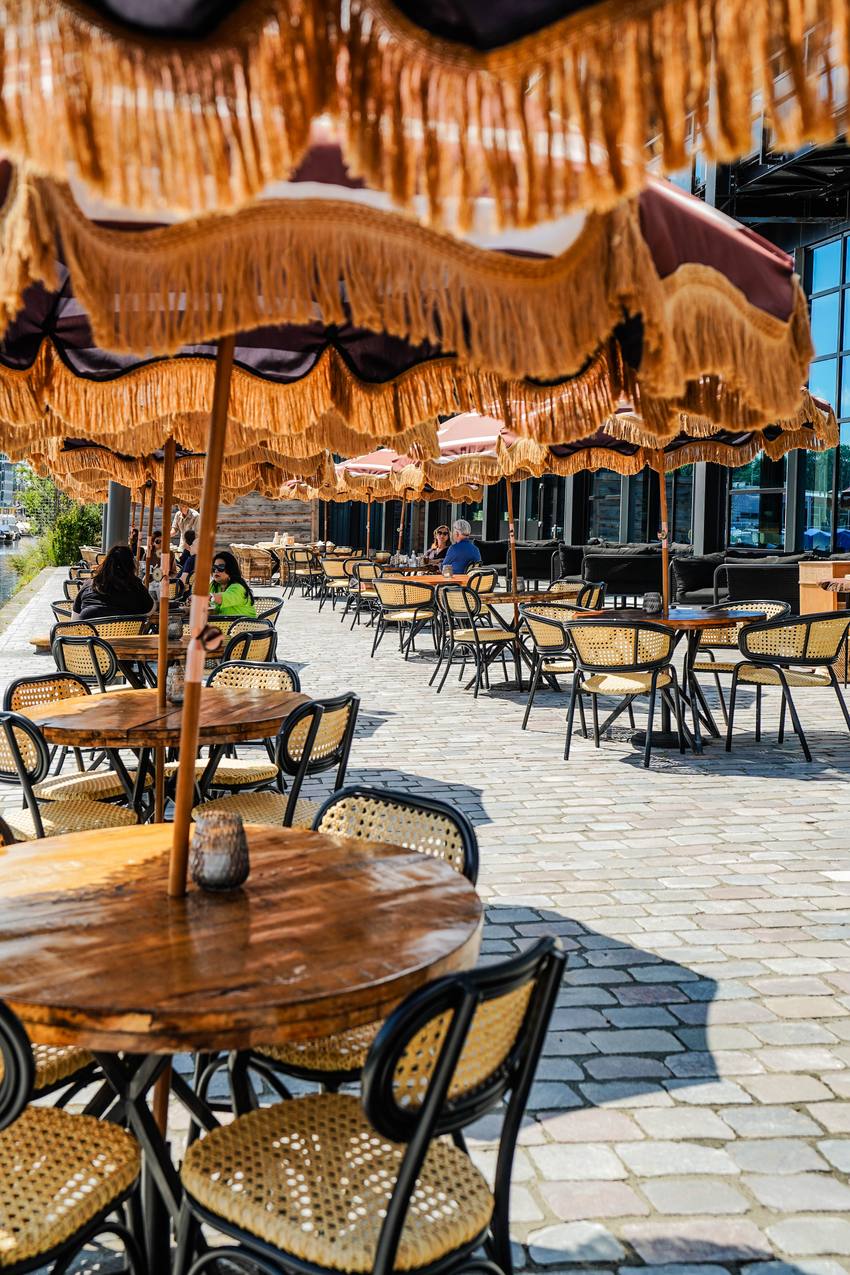 Rij terrastafels onder de franjeparasols